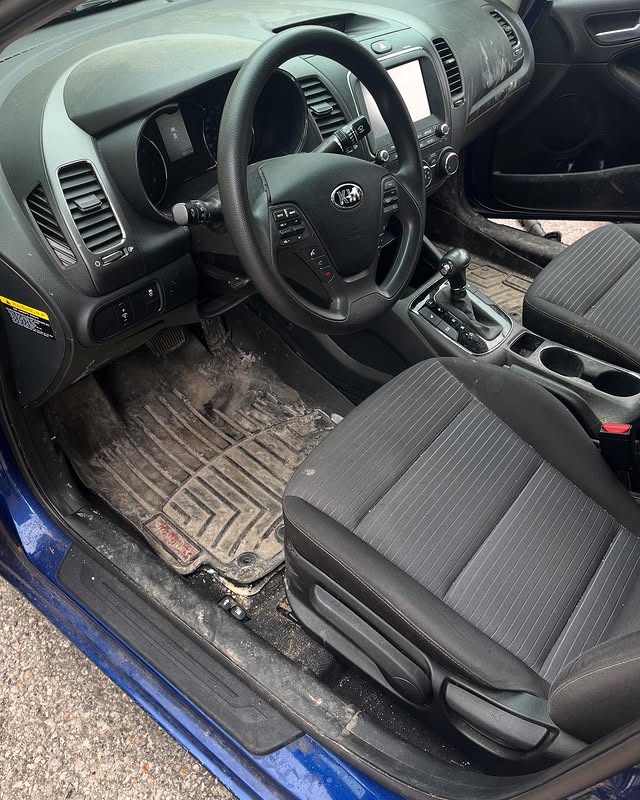 Before: Dirty Kia Forte driver side with salt-covered floor mats